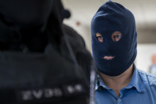 Kľ&uacute;čov&yacute; svedok Zolt&aacute;n Andrusk&oacute; v kukle prich&aacute;dza v sprievode pr&iacute;slu&scaron;n&iacute;kov Zboru v&auml;zenskej a justičnej str&aacute;že na s&uacute;dne pojedn&aacute;vanie v kauze objedn&aacute;vky vraždy novin&aacute;ra J&aacute;na Kuciaka. FOTO: TASR/Martin Baumann