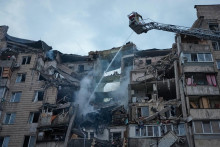 Hasiči zasahuj&uacute; na mieste po&scaron;kodenej obytnej budovy po ruskom &uacute;toku na Kyjev. FOTO: TASR/AP