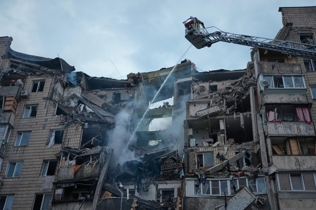 Hasiči zasahuj&uacute; na mieste po&scaron;kodenej obytnej budovy po ruskom &uacute;toku na Kyjev. FOTO: TASR/AP
