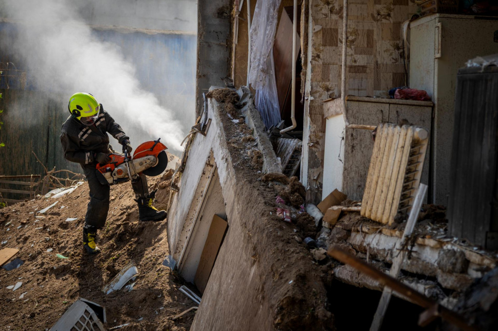 Ukrajinsk&yacute; hasič pracuje pred po&scaron;kodenou budovou. FOTO: TASR/AP