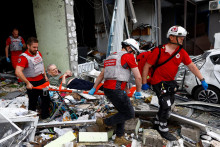 Dobrovoľn&iacute;ci Červen&eacute;ho kr&iacute;ža vyn&aacute;&scaron;aj&uacute; osobu z bytov&eacute;ho domu, ktor&yacute; bol ťažko po&scaron;koden&yacute; počas rusk&yacute;ch &uacute;tokov v Kyjeve. FOTO: Reuters