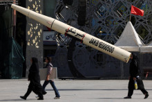 Ľudia kr&aacute;čaj&uacute; vedľa symbolickej makety ir&aacute;nskej rakety v Teher&aacute;ne. FOTO: Reuters/WANA