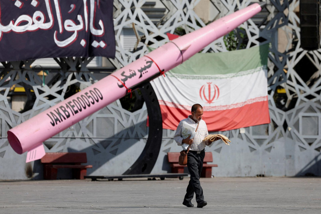 Muž kr&aacute;ča vedľa symbolickej makety ir&aacute;nskej rakety a ir&aacute;nskej vlajky v Teher&aacute;ne. FOTO: Reuters/WANA