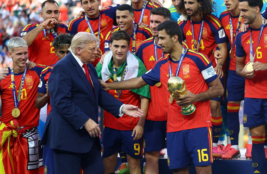 &Scaron;panielsky reprezentant Rodri sa rozpr&aacute;va s americk&yacute;m prezidentom Donaldom Trumpom, pričom drž&iacute; trofej z majstrovstiev sveta spolu so svojimi spoluhr&aacute;čmi, ktor&iacute; oslavuj&uacute; v&iacute;ťazstvo na Majstrovstv&aacute;ch sveta. FOTO: REUTERS