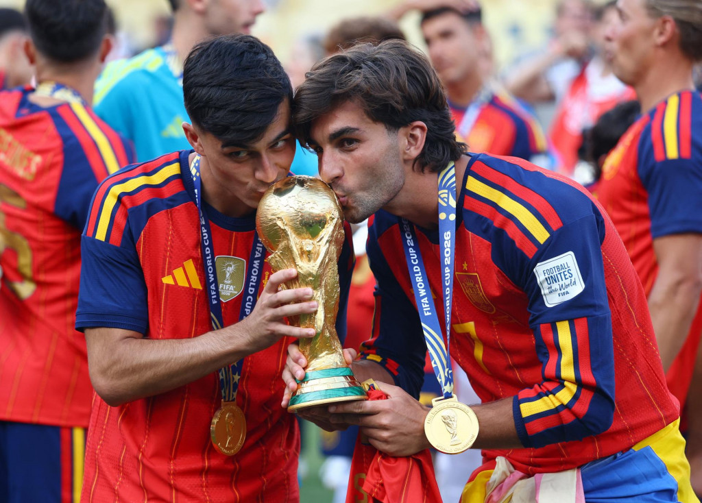&Scaron;panieli Pedri a Ferran Torres bozk&aacute;vaj&uacute; trofej pri oslave v&iacute;ťazstva na MS vo futbale. FOTO: REUTERS