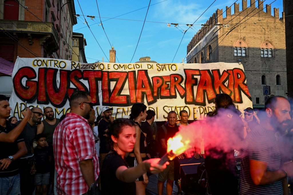 Protestuj&uacute;ci drž&iacute; svetlicu pred transparentom s n&aacute;pisom v taliančine &bdquo;Spravodlivosť pre Fakira&ldquo; počas protestu po smrti v Bologni. FOTO: Reuters