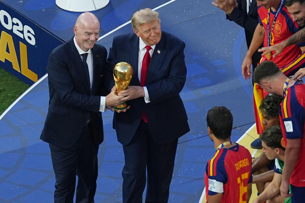 Americk&yacute; prezident Donald Trump a &scaron;&eacute;f Medzin&aacute;rodnej futbalovej feder&aacute;cie (FIFA) Gianni Infantino stoja s trofejou pri &scaron;panielskych futbalistoch, ktor&iacute; oslavuj&uacute; so zlat&yacute;mi medailami triumf na majstrovstv&aacute;ch sveta vo futbale. FOTO: TASR/AP