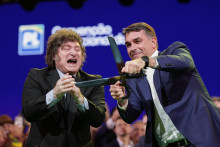 Braz&iacute;lsky sen&aacute;tor Flavio Bolsonaro (vpravo) drž&iacute; v ruk&aacute;ch obrovsk&eacute; nožnice vedľa argent&iacute;nskeho prezidenta Javiera Mileiho počas zjazdu Liber&aacute;lnej strany, na ktorom Bolsonara zvolili za prezidentsk&eacute;ho kandid&aacute;ta strany v Sao Paule v sobotu 25. j&uacute;la 2026. FOTO TASR/AP
