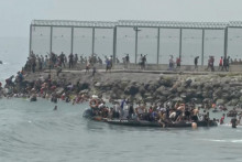 Migranti sa zhromažďuj&uacute; na a okolo lode Civilnej gardy v &scaron;panielskej Ceute. FOTO: Reuters