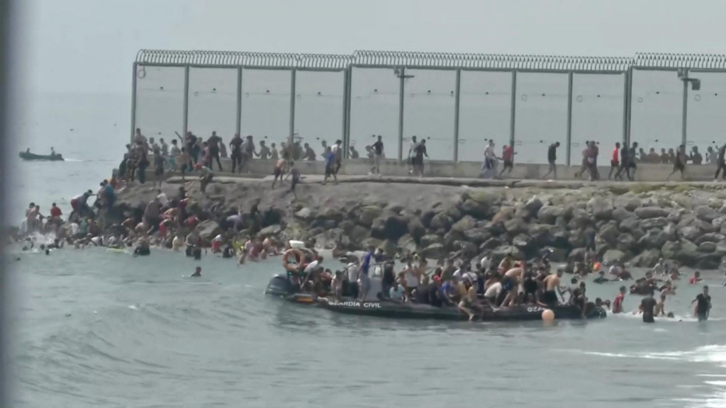 Migranti sa zhromažďuj&uacute; na a okolo lode Civilnej gardy v &scaron;panielskej Ceute. FOTO: Reuters