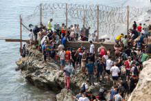 Migranti prech&aacute;dzaj&uacute; cez ostnat&yacute; dr&ocirc;t pri pokuse prekročiť hranicu z Maroka do &scaron;panielskej enkl&aacute;vy Ceuta. FOTO: TASR/AP