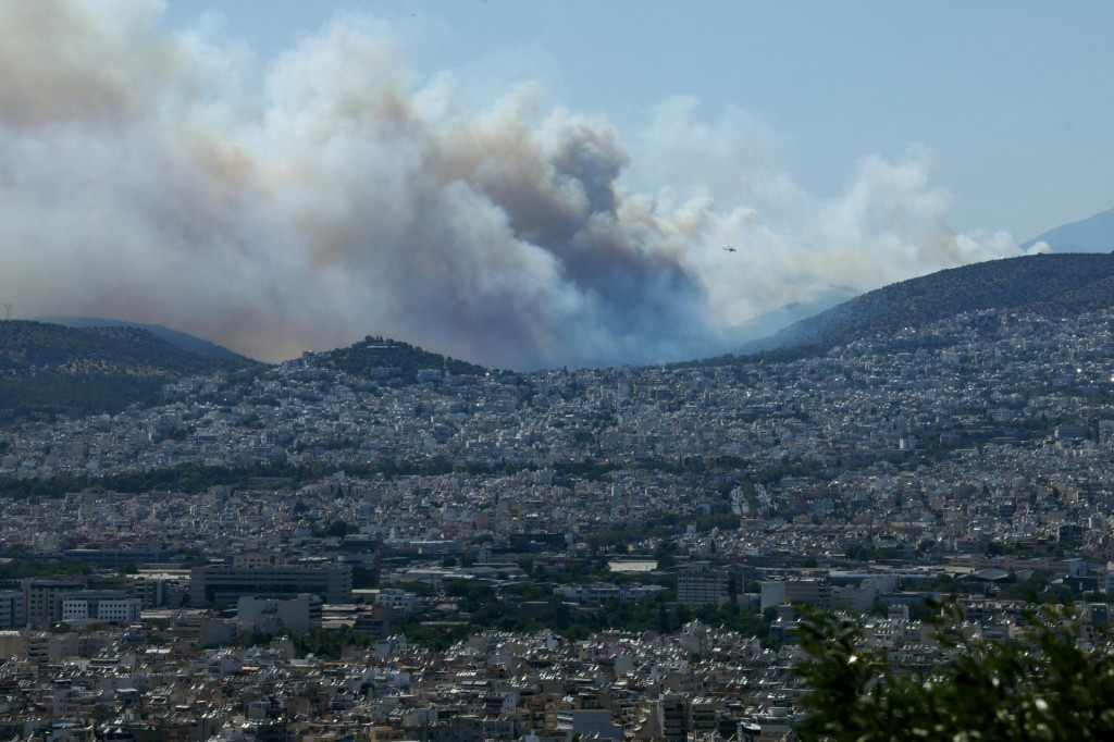 Dym z lesn&eacute;ho požiaru horiaceho neďaleko Haidari zahalil At&eacute;ny v Gr&eacute;cku. FOTO: Reuters