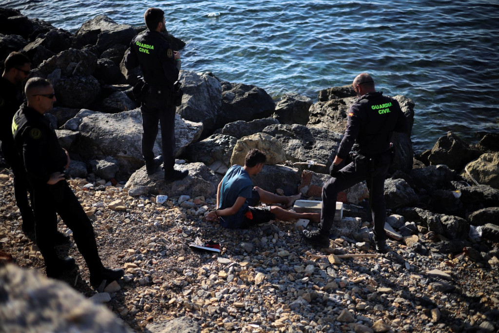 Pr&iacute;slu&scaron;n&iacute;ci &scaron;panielskej Civilnej gardy zadržiavaj&uacute; migranta uprostred hromadn&eacute;ho prechodu migrantov pe&scaron;o a po mori z Maroka na &scaron;panielske &uacute;zemie v Ceute v &Scaron;panielsku. FOTO: Reuters