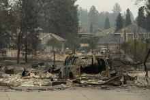 Vrak auta a budovy, ktor&eacute; po&scaron;kodil lesn&yacute; požiar v meste Spokane v americkom &scaron;t&aacute;te Washington. FOTO: TASR/AP