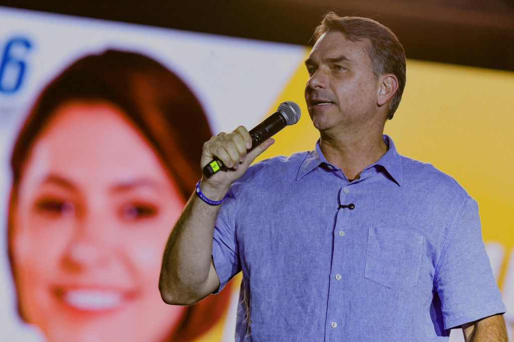 Braz&iacute;lsky prezidentsk&yacute; kandid&aacute;t sen&aacute;tor Flavio Bolsonaro stoj&iacute; pred obr&aacute;zkom Michelle Bolsonarovej, manželky b&yacute;val&eacute;ho prezidenta Jaira Bolsonara. FOTO: Reuters