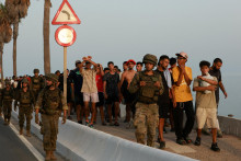Pr&iacute;slu&scaron;n&iacute;ci arm&aacute;dy eskortuj&uacute; migrantov v Ceute po ned&aacute;vnom hromadnom prekročen&iacute; hranice. FOTO: Reuters
