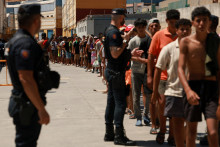 Migranti stoja v rade, aby si od miestnej mimovl&aacute;dnej organiz&aacute;cie Media Luna Blanca prevzali z&aacute;kladn&eacute; potraviny v priemyselnej z&oacute;ne v &scaron;panielskej Ceute. FOTO: Reuters
