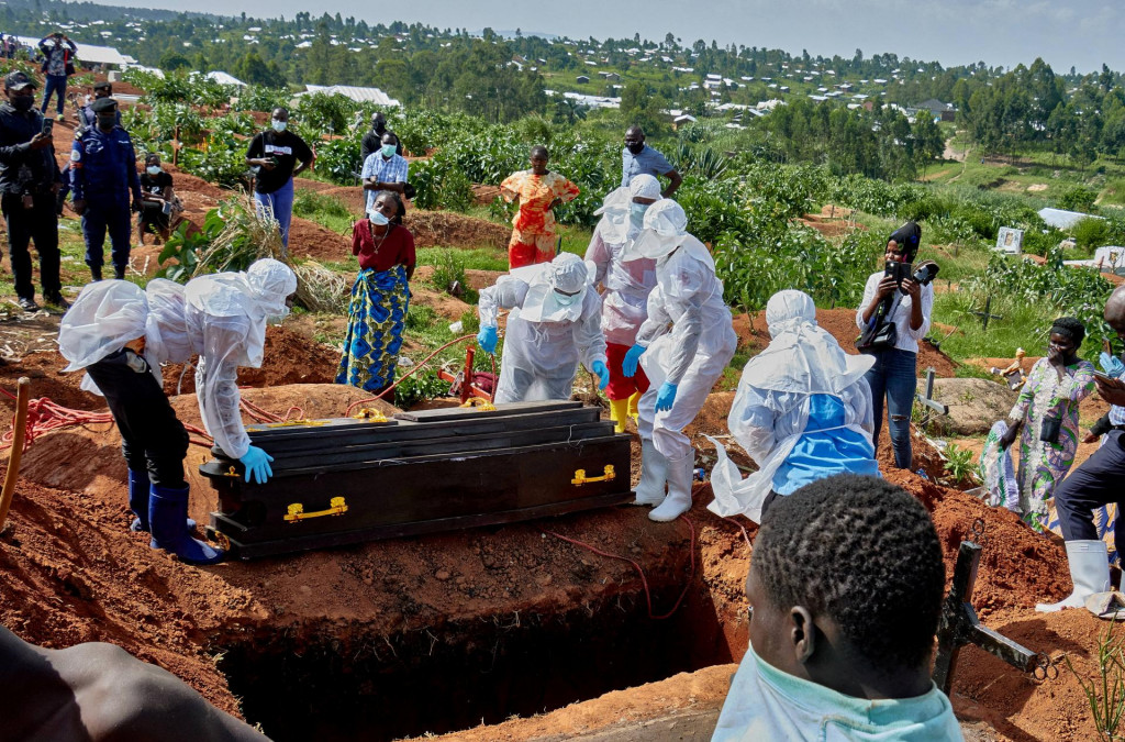 Pracovn&iacute;ci Červen&eacute;ho kr&iacute;ža v osobn&yacute;ch ochrann&yacute;ch prostriedkoch sa pripravuj&uacute; spustiť rakvu osoby, ktor&aacute; zomrela na v&iacute;rus Ebola. FOTO: Reuters