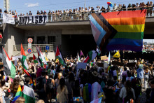 Protidemon&scaron;tranti ukazuj&uacute; transparent proti LGBT+ ľuďom s veľkou vlajkou Pride, zatiaľ čo ľudia sa z&uacute;častňuj&uacute; Prague Pride. FOTO: Reuters