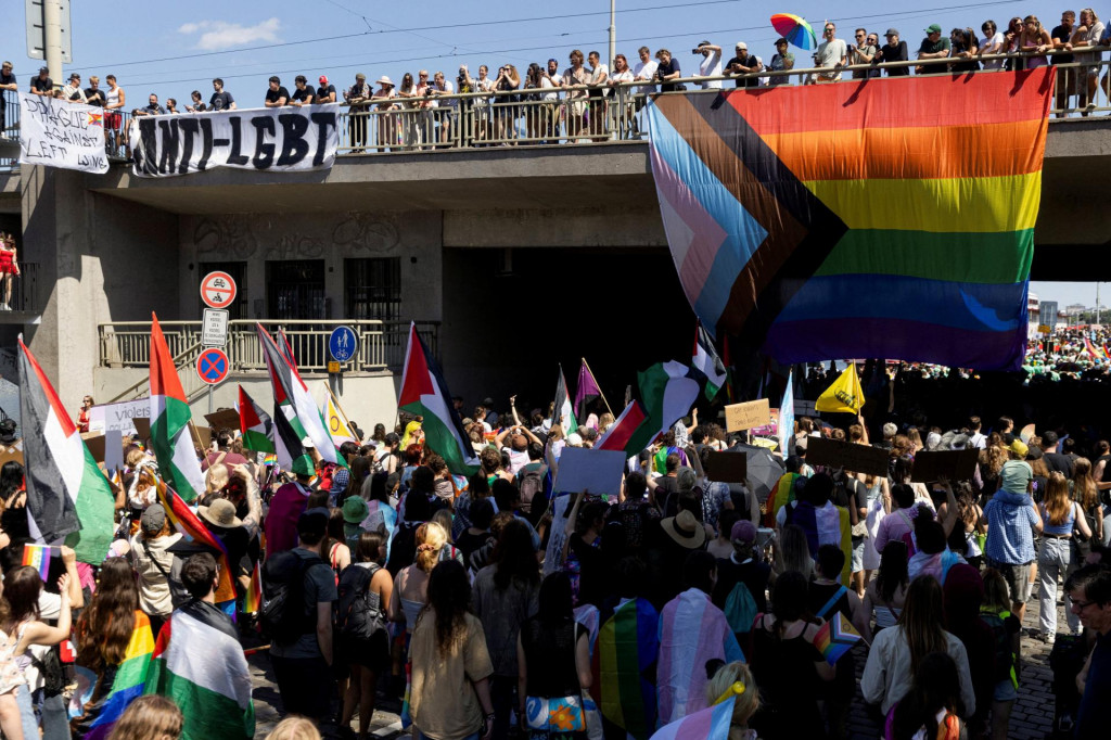 Protidemon&scaron;tranti ukazuj&uacute; transparent proti LGBT+ ľuďom s veľkou vlajkou Pride, zatiaľ čo ľudia sa z&uacute;častňuj&uacute; Prague Pride. FOTO: Reuters