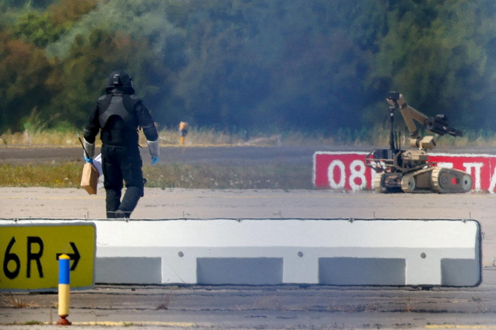 Policajt v ochrannom oblečen&iacute; kr&aacute;ča vedľa robota na zne&scaron;kodňovanie v&yacute;bu&scaron;n&iacute;n na letisku Lipsko/Halle v Schkeuditz v Nemecku (5. augusta 2026). FOTO: Reuters
