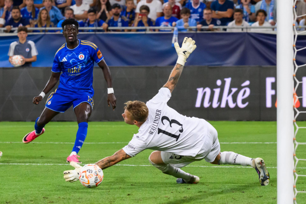Na sn&iacute;mke sprava brank&aacute;r Robin Wallinder (Fj&auml;llby), ktor&eacute;mu strieľa g&oacute;l Alasana Yirajang (Slovan) počas odvety 3. predkola Ligy majstrov vo futbale. FOTO: TASR/Jaroslav Nov&aacute;k