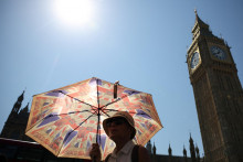 Žena sa počas vlny hor&uacute;čav v Lond&yacute;ne v Brit&aacute;nii chr&aacute;ni pred slnkom d&aacute;ždnikom. FOTO: Reuters