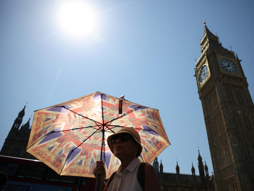Žena sa počas vlny hor&uacute;čav v Lond&yacute;ne v Brit&aacute;nii chr&aacute;ni pred slnkom d&aacute;ždnikom. FOTO: Reuters
