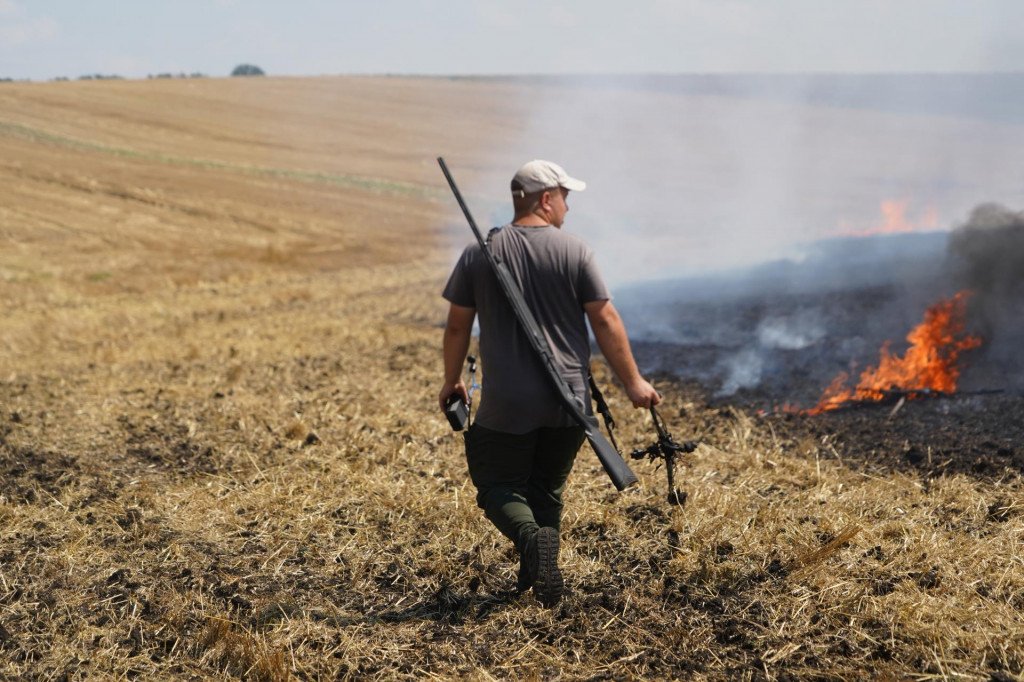 Na sn&iacute;mke farm&aacute;r nesie časť rusk&eacute;ho dronu, ktor&yacute; zostrelil pu&scaron;kou a sleduje horiace pole po dronovom &uacute;toku ruskej arm&aacute;dy v Charkovskej oblasti na v&yacute;chode Ukrajiny. FOTO: TASR/AP