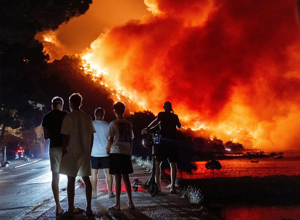Ľudia sleduj&uacute; lesn&yacute; požiar na pobrež&iacute; Jadransk&eacute;ho mora neďaleko mesta Omi&scaron; na juhu Chorv&aacute;tska. FOTO: TASR/AP