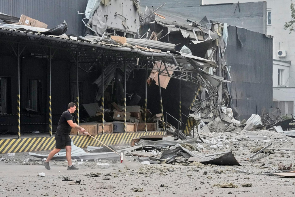 Zamestnanec po&scaron;ty upratuje pred po&scaron;koden&yacute;m veľkoskladom po&scaron;ty po ruskom leteckom &uacute;toku v Kyjeve v stredu 5. augusta 2026. FOTO: TASR/AP