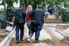 Policajti odv&aacute;dzaj&uacute; podporovateľku strany Jabloko pred budovou Najvy&scaron;&scaron;ieho s&uacute;du, kde sa kon&aacute; odvolacie pojedn&aacute;vanie. FOTO: Reuters