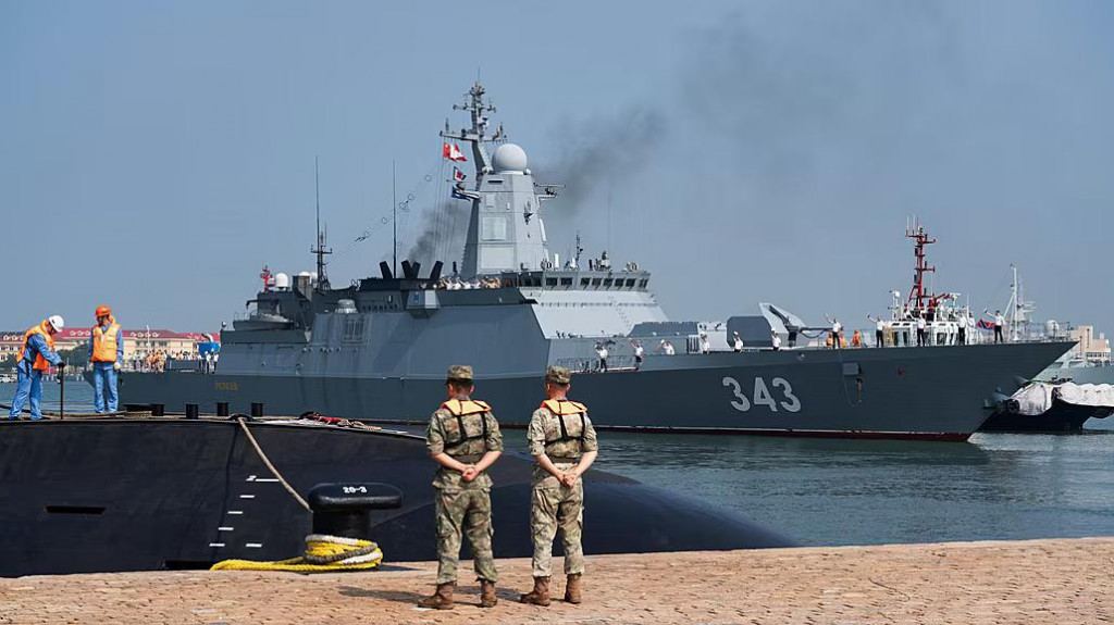 Č&iacute;nski vojaci stoja na str&aacute;ži, zatiaľ čo rusk&aacute; korveta mieri do vojensk&eacute;ho pr&iacute;stavu v Čching-tao na v&yacute;chode Č&iacute;ny, aby sa z&uacute;častnila cvičenia &bdquo;Joint Sea-2026&ldquo;. FOTO: TASR/ASP