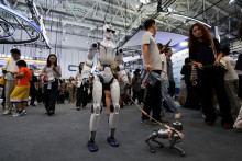 Humanoidn&yacute; robot R1 od spoločnosti Unitree kr&aacute;ča s robotick&yacute;m psom počas Svetovej konferencie o robotoch 2026 v Pekingu v Č&iacute;ne 19. augusta 2026. FOTO: Reuters