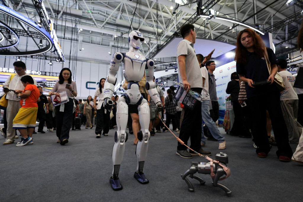 Humanoidn&yacute; robot R1 od spoločnosti Unitree kr&aacute;ča s robotick&yacute;m psom počas Svetovej konferencie o robotoch 2026 v Pekingu v Č&iacute;ne 19. augusta 2026. FOTO: Reuters