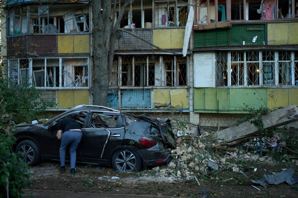 Miestny obyvateľ sa pozer&aacute; do vn&uacute;tra po&scaron;koden&eacute;ho osobn&eacute;ho auta pred obytnou budovou v ukrajinskej metropole Kyjev. FOTO TASR/AP
