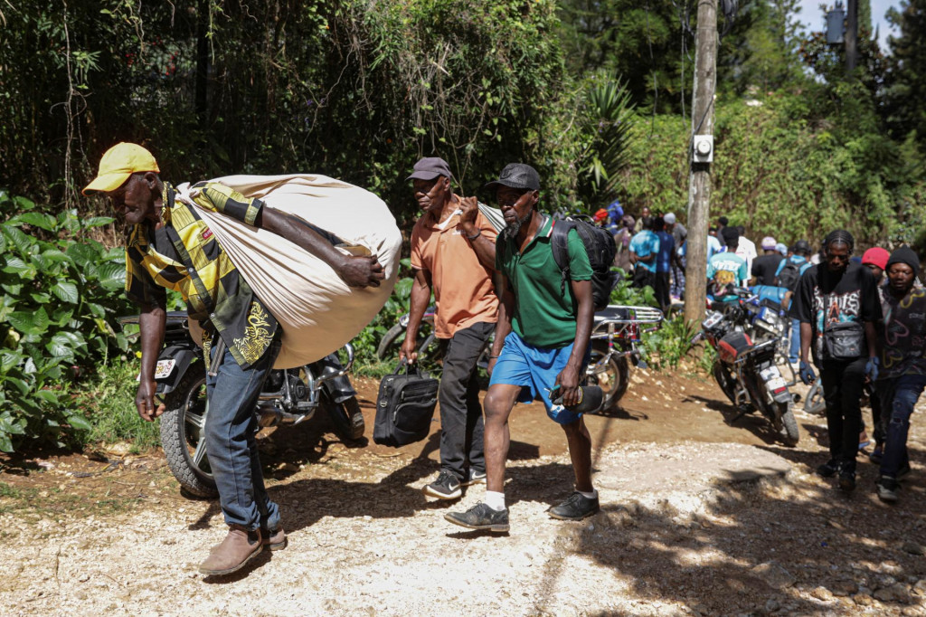 Ľudia nes&uacute; svoje veci, keď utekaj&uacute; zo svojich domovov po nočnom &uacute;toku ozbrojen&eacute;ho gangu na okraji Port-au-Prince. FOTO: Reuters