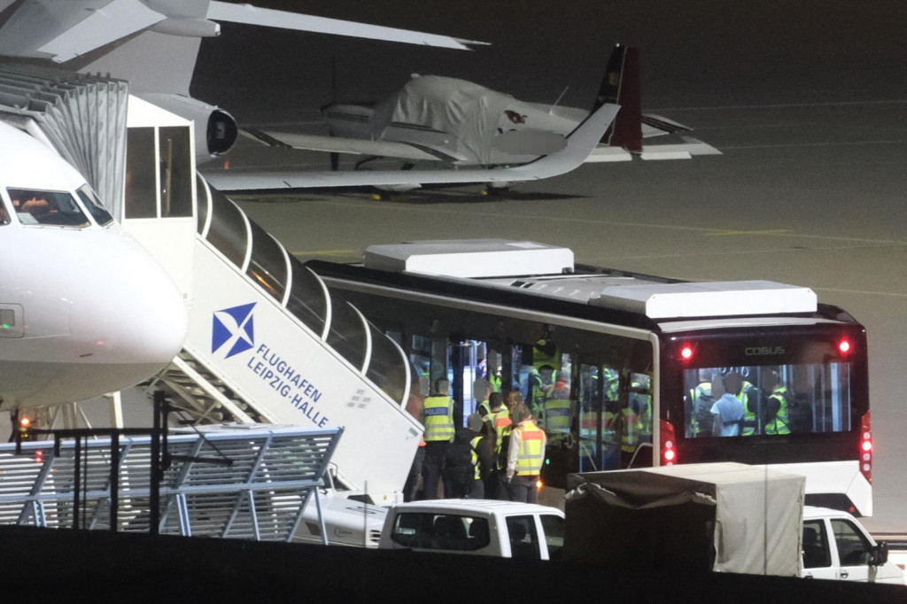 Autobus, v ktorom sedia afgansk&iacute; muži, stoj&iacute; pri lietadle na letisku Lipsko/Hallee. FOTO: TASR/DPA