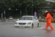 Auto jazd&iacute; po zaplavenej ulici po prudk&yacute;ch dažďoch v japonskom meste Himi. FOTO: TASR/AP