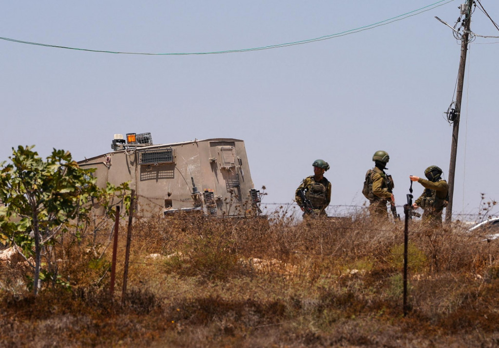 Izraelsk&iacute; vojaci stoja pri palest&iacute;nskom dome, ktor&yacute; obliehali izraelsk&iacute; osadn&iacute;ci v dedine Kusra na Izraelom okupovanom Z&aacute;padnom brehu Jord&aacute;nu. FOTO: Reuters