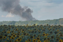 Dym st&uacute;pa nad skladov&yacute;mi halami za poľom slnečn&iacute;c po leteckom &uacute;toku ruskej arm&aacute;dy na Kyjev. FOTO: TASR/AP