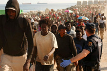 Migrantov eskortuj&uacute; z proviz&oacute;rneho pl&aacute;žov&eacute;ho t&aacute;bora do ofici&aacute;lnych &uacute;tulkov na druhej strane mesta po tom, čo &uacute;rady vyčistili miesto v &scaron;panielskej severoafrickej enkl&aacute;ve Ceuta. FOTO: Reuters