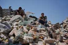 Palest&iacute;nčania sa pozeraj&uacute; na zničen&yacute; sklad s potravinovou pomocou po izraelsk&yacute;ch leteck&yacute;ch &uacute;tokoch v meste Dajr al-Balah, v centr&aacute;lnom P&aacute;sme Gazy. FOTO: TASR/AP