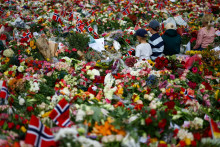 Deti sedia medzi kvetmi pred Kr&aacute;ľovsk&yacute;m pal&aacute;com, ktor&eacute; položili ľudia na znak &uacute;cty k zosnul&eacute;mu n&oacute;rskemu kr&aacute;ľovi Haraldovi. FOTO: Reuters