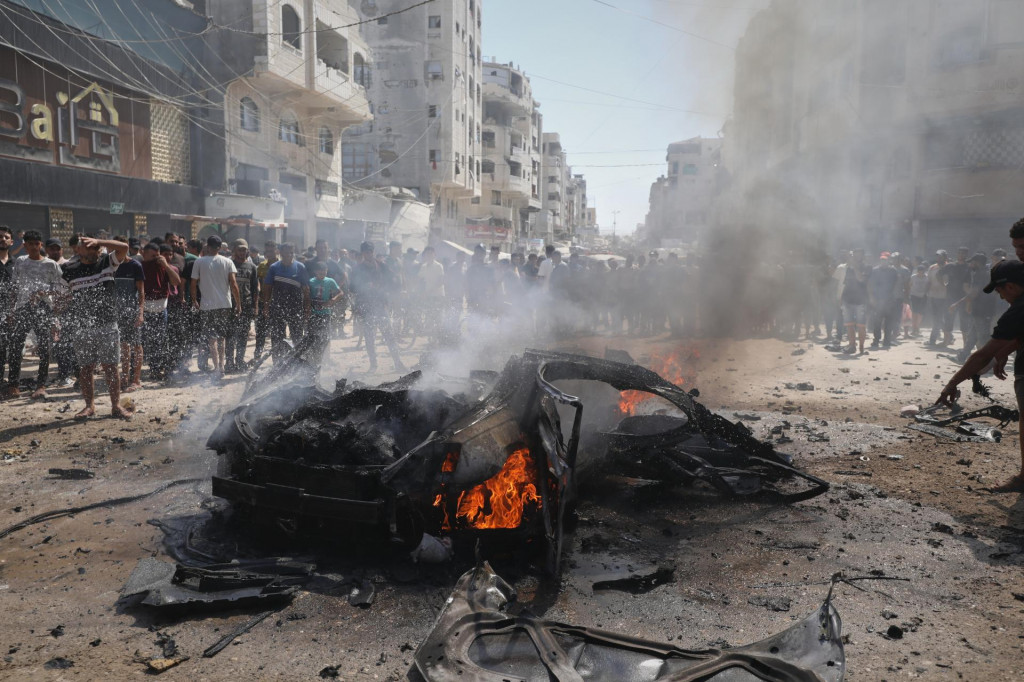 Na sn&iacute;mke Palest&iacute;nčania sa zhromaždili okolo horiaceho vraku auta po &uacute;toku izraelskej arm&aacute;dy v meste Gaza v pondelok 31. augusta 2026. FOTO: TASR/AP