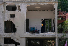 Žena kontroluje trosky zničen&eacute;ho domu na mieste, ktor&eacute; zasiahla raketa po izraelsk&yacute;ch leteck&yacute;ch &uacute;tokoch v dedine Arab Sal&iacute;m, na juhu Libanonu. FOTO: TASR/AP