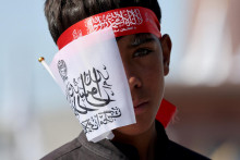 Chlapec pred&aacute;va vlajky Islamsk&eacute;ho emir&aacute;tu Afganistan počas osl&aacute;v piateho v&yacute;ročia n&aacute;vratu Talibanu, ktor&eacute; sa v K&aacute;bule konali 15. augusta. FOTO: Reuters