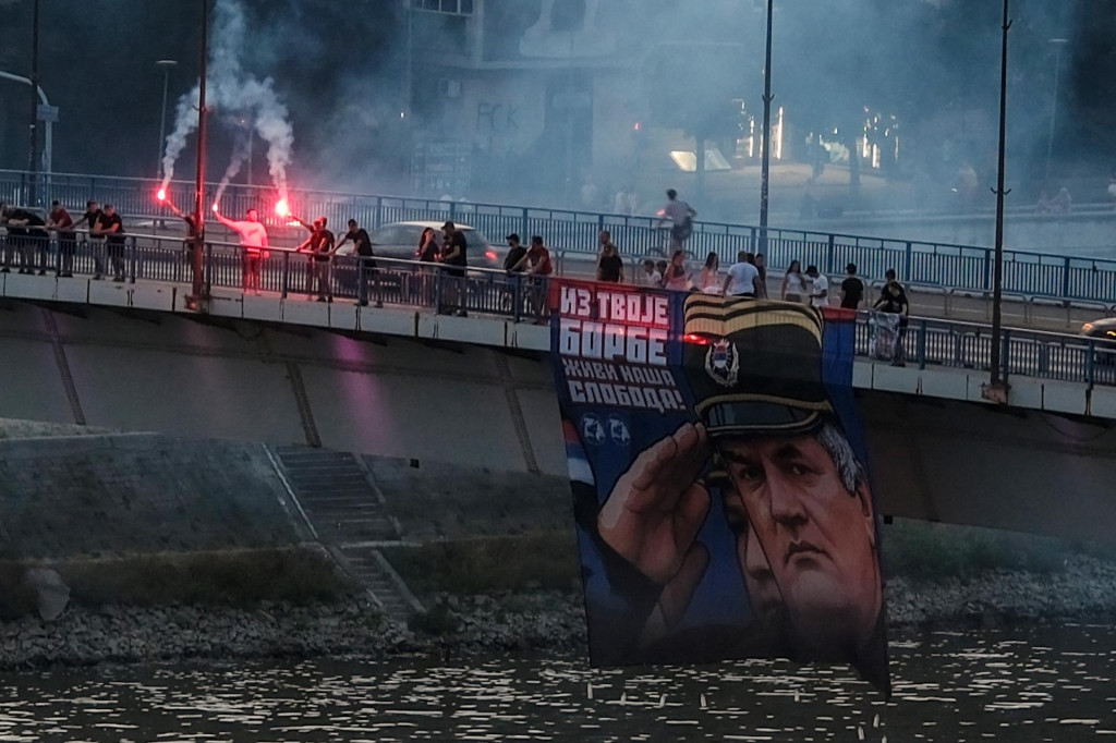 Podporovatelia zosnul&eacute;ho bosnianskosrbsk&eacute;ho gener&aacute;la Ratka Mladića držia jeho obraz a zapaľuj&uacute; svetlice na Varadinskom moste v Novom Sade v Srbsku. FOTO: Reuters