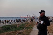 Migranti čakaj&uacute; v rade na v&yacute;daj potrav&iacute;n Červen&yacute;m kr&iacute;žom na pl&aacute;ži Trampolin po ned&aacute;vnych masov&yacute;ch prechodoch migrantov z Maroka do Ceuty. FOTO: Reuters