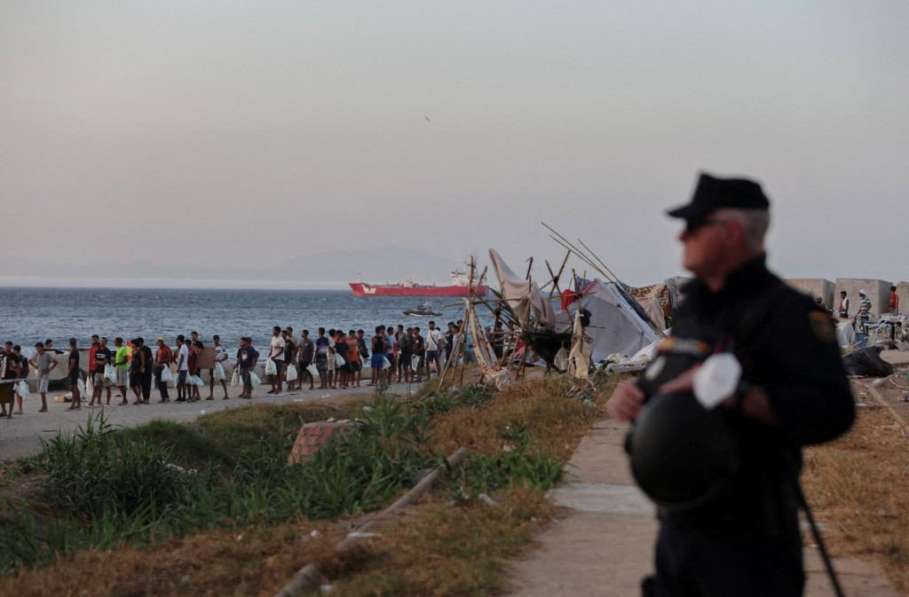 Migranti čakaj&uacute; v rade na v&yacute;daj potrav&iacute;n Červen&yacute;m kr&iacute;žom na pl&aacute;ži Trampolin po ned&aacute;vnych masov&yacute;ch prechodoch migrantov z Maroka do Ceuty. FOTO: Reuters